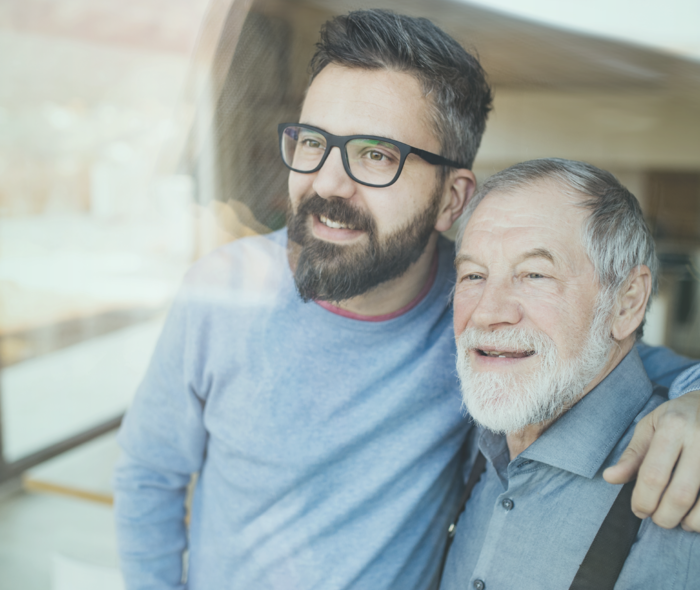 Leben mit metastasiertem Prostatakarzinom: Ein junger Mann mit Brille steht neben einem älteren Herren und legt seinen Arm um dessen Schulter. Ein junger Mann mit Brille steht neben einem älteren Herren und legt seinen Arm um dessen Schulter.